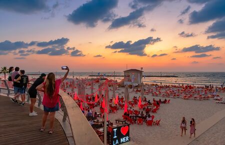 A young woman taking a picture of the sunset using the mobile phone.のeditorial素材