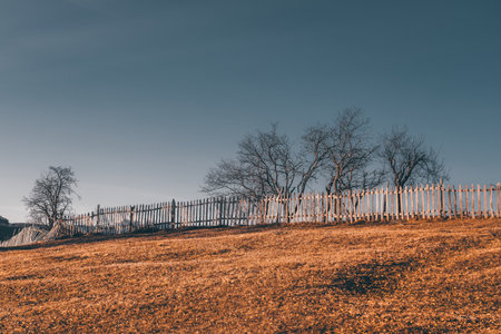Rural landscape with wooden fence and trees on the hill.の写真素材