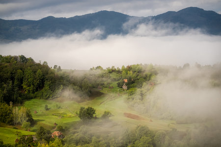 Landscape with green hills and village in foggy morning.の写真素材