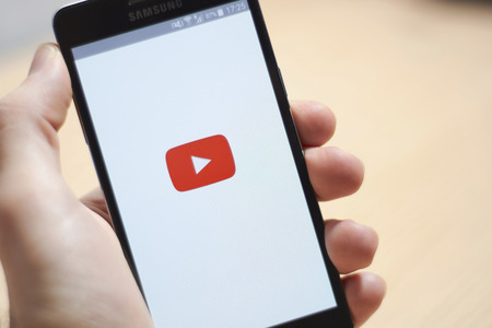 BUENOS AIRES, ARGENTINA - JANUARY 9, 2019: Hand holding a mobile phone showing the YouTube logo of the mobile application.のeditorial素材