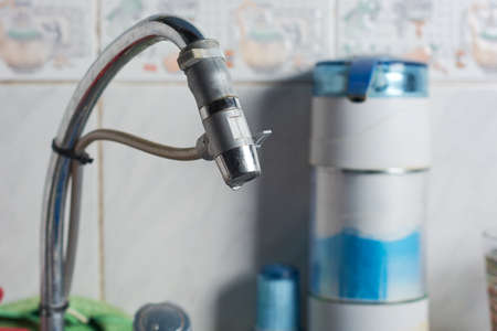 Closeup of modern water purifier installed on water tap in the kitchen of a house.の写真素材