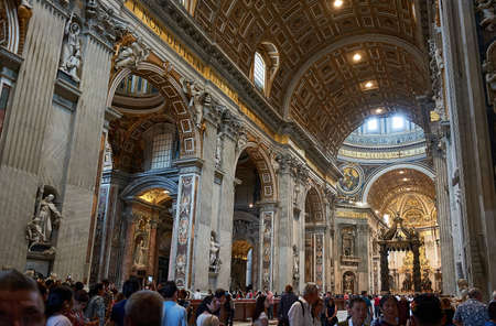VATICAN CITY, VATICAN - MAY 17, 2017: Interior view of the Basilica of Saint Peter in the Vatican with sculptures, roof and crowd of people visiting the main altar (Baldachin, by Bernini).のeditorial素材