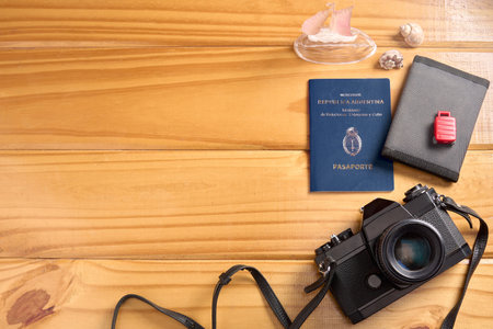 Top view of Argentine passport and travel accessories on table. Camera, wallet, miniature suitcase and embarkation, and seashells. Argentina travel documentation. Copyspace.の写真素材
