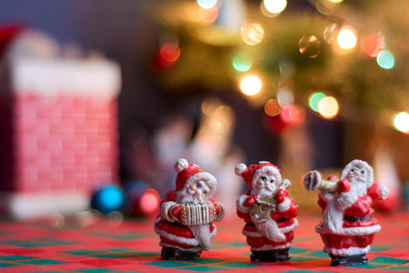 Miniature ornaments of Santa Claus playing musical instruments with blurred decoration and Christmas tree in the background, beautiful bokeh with Christmas lights. Copy spaceの写真素材