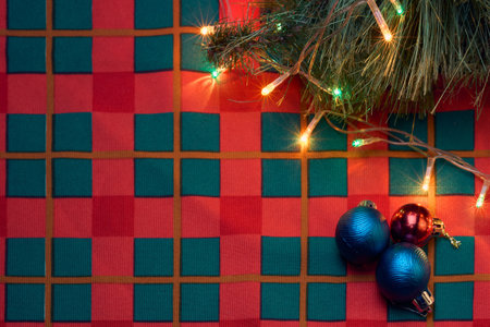 Top view of Christmas decoration on table with red and green tablecloth. Christmas balls, tree and lights on table, background with copy space for text.の写真素材