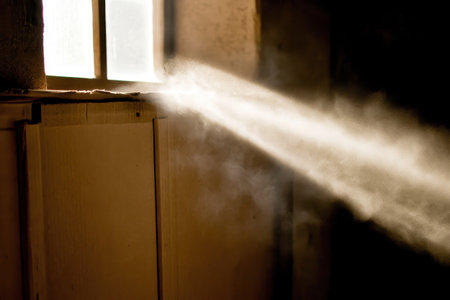 Sunlight streaming through small window onto dusty cardboard interior. AI-generatedの素材