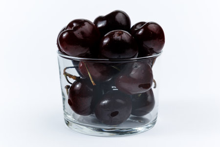 Picota cherries in a clear glass on white background.