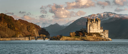 Panoramic view of Eilean Donan Castle on the east coast of Scotland in the sun, with snow on the...