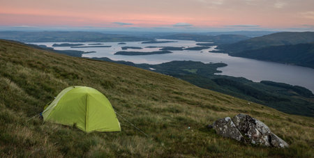 Green tent wild camping on Ben Lomond in the evening, on the slope of the hill overlooking the lake, Loch Lomond and The Trossachs National Park, Scotlandの写真素材