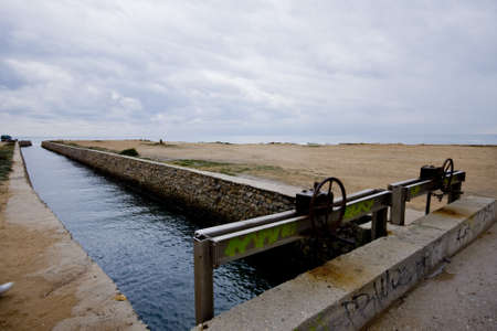 A channel flows into the sea across the beachの写真素材