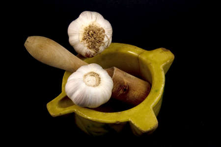 Displays a ceramic mortar with pestle and garlic.の写真素材
