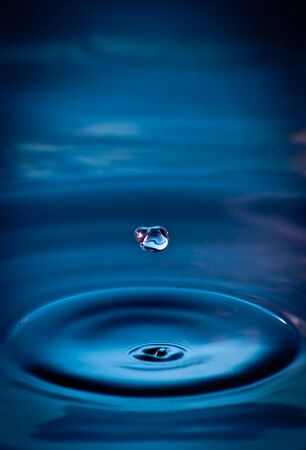 Peacefull droplet falling into a pool of cool waterの写真素材