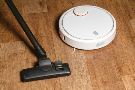 old vacuum cleaner and new robot vacuum cleaner on the floorの写真素材