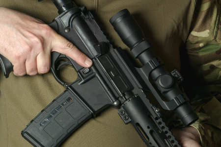 A soldier holding a rifle with a telescopic sight