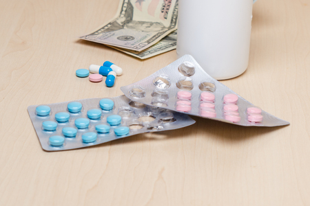 Blue and pink pills and dollars on the tableの写真素材