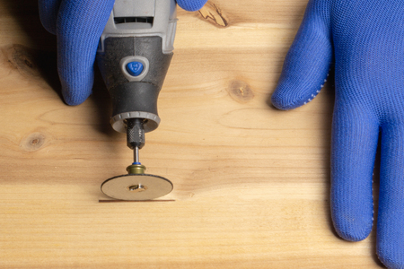 carpenter in blue protective gloves handles wooden dremelの写真素材