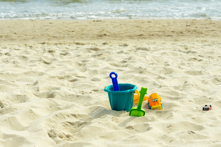 Multi-colored childrens toys in the sand by the seaの写真素材