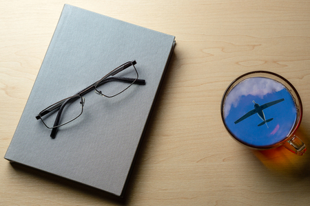 A cup of tea with a reflection of the aircraft in the sky on the office deskの写真素材