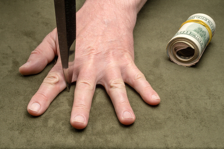 Knife between the fingers of a mans handの写真素材