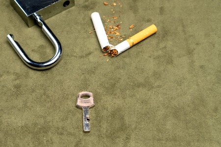Exemption from bad habits. The key on the background of a broken cigarette and an open lockの写真素材