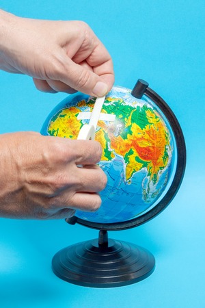 Male hand putting a patch on a globe.