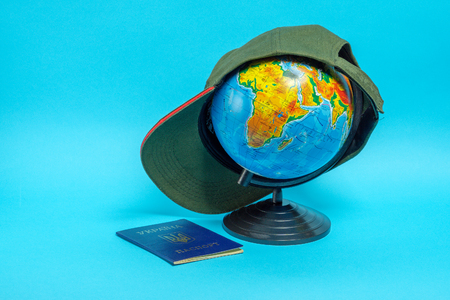 Passport of a citizen of Ukraine near the globe with a baseball cap. Geographical names on the globe in Russianの写真素材