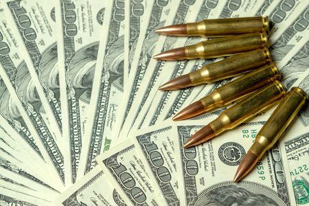 Rifle cartridges on dollars. Concept for crime, contract killing, paid assassin, terrorism, war, global arms trade, weapons sale. Illegal hunting, poachingの写真素材