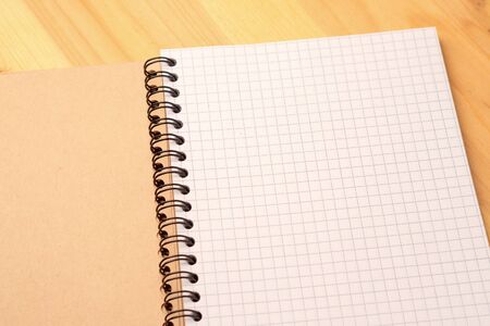 Notebook with checkered sheets on a wooden table. Top viewの写真素材