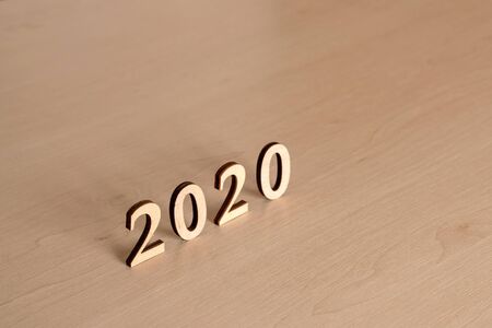 2020 Happy New Year. 2020 made from wooden letters, standing on a wooden table, top view. Concept...