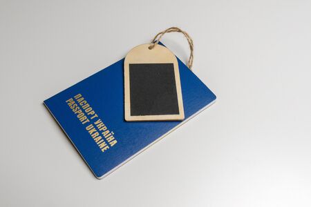 Wooden tag with a blue passport on a white table.の写真素材