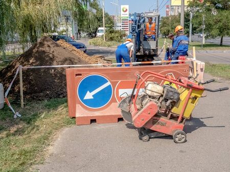 Odessa, Ukraine - August 22, 2019: Road work on the sidewalk. Warning road signs on the fence around...