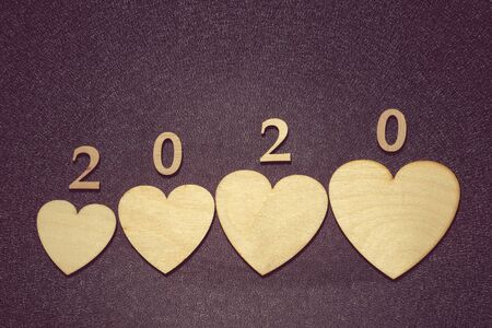 Four wooden hearts and the inscription 2020 on a blackboard. The concept of family development,...