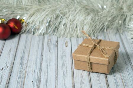 Gift box on a wooden table decorated with a garland and red Christmas balls for the New Year or XMAS. Mail, courier or delivery service concept. Copy spaceの写真素材