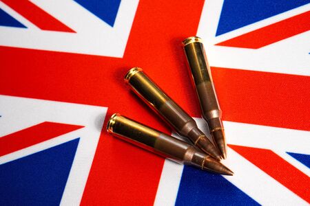 Three rifle cartridges on the flag of Great Britain. Close-up, copy space