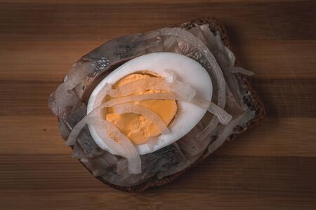 Sandwich with herring, onions and chicken egg on a wooden tray. National Russian cuisine, top viewの写真素材