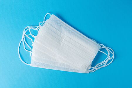 White medical masks on a blue background, top view