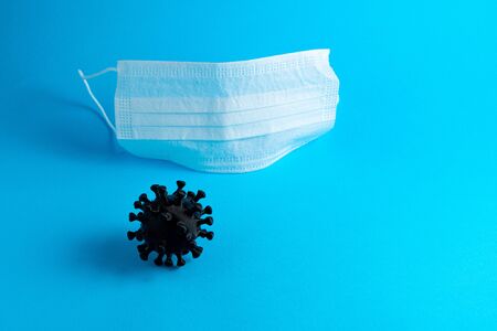 White medical mask on a blue background and coronavirus, copy space. Pandemic COVID-19の写真素材