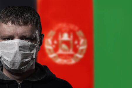 Portrait of a white man in a medical mask on the background of the flag of Afghanistanの写真素材