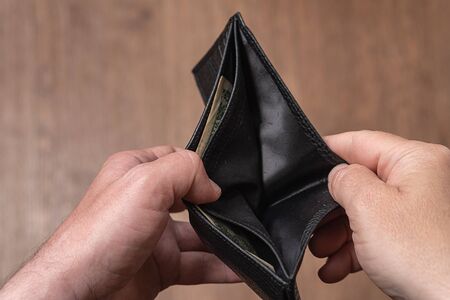 Empty leather wallet in the hands of a man, close-up. Poverty concept.