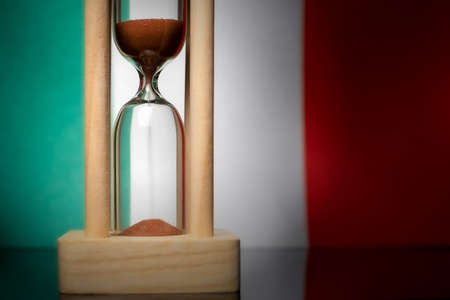 Hourglass and Italy flag, soft focus, copy space