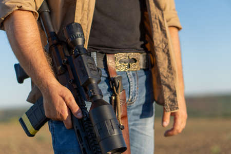 A rifle in a mans hand, close-up. Hunter with a weapon on the hunt against the background of a...