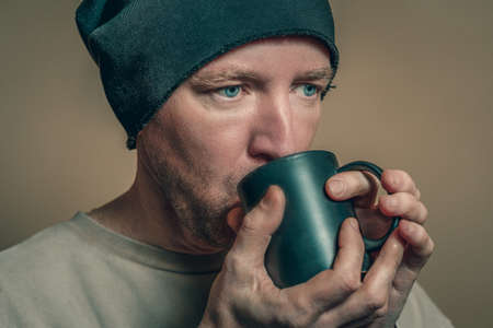 Portrait of a man in a black hat with a black cup, close-upの写真素材