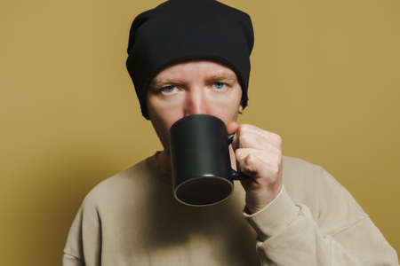 Portrait of a man in a black hat with a black cup, close-up