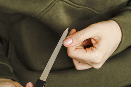 Female hands with manicure hold a nail treatment toolの写真素材