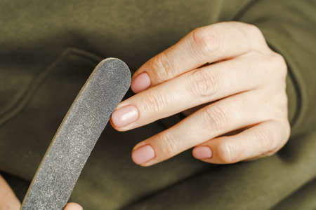 Female hands with manicure hold a nail treatment tool