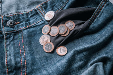 Several euro coins in the pocket of old jeans. Symbol for crisis or cost of living or bankruptcyの写真素材