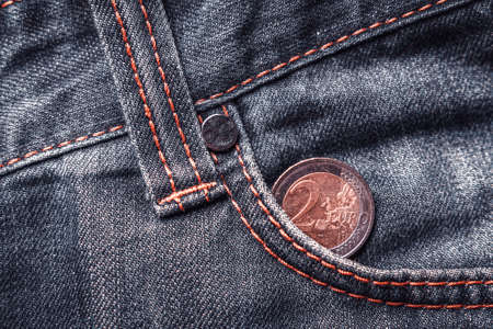 Two euro coin in the pocket of old shabby jeans.の写真素材