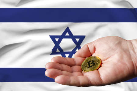 Golden bitcoin coin in man's hand, Israel flag in the background.