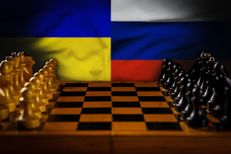 War in Ukraine, war of Ukraine against Russia. Chessboard with white and black pieces, background of the flags of Ukraine and Russia. Soft focus, copyspaceの写真素材