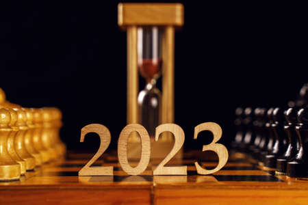The number 2023 and hourglassin the center of the chessboard, black and white pieces. Happy New Year, blank for design. Soft focus, copyspaceの写真素材